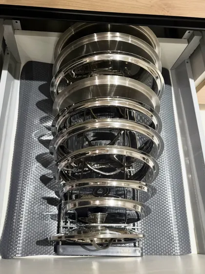 A unique vertical storage solution for steel lids and plates. This pull-out rack is an excellent use of a narrow cabinet space, keeping items secure and accessible.