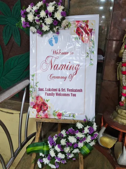 A beautiful welcome board for a naming ceremony, framed with an elegant floral arrangement.