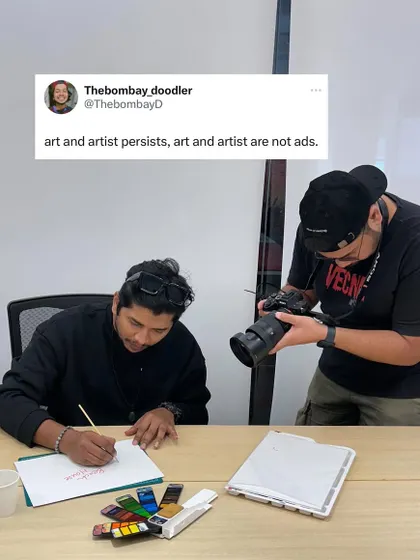 A behind-the-scenes shot during a photoshoot. As the tweet says, "art and artist persists, art and artist are not ads." It's about the passion and the process.