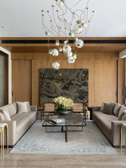 The main seating area in the K Residence living room, centered around a large Vibha Galhotra artwork and a stunning Bocci light installation. The arrangement of two sofas creates a formal yet welcoming space, perfect for hosting guests in an environment of curated elegance.