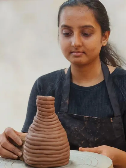 Using the coiling method, a student builds up the walls of a vase layer by layer. This ancient technique is versatile for creating a wide variety of shapes and sizes.