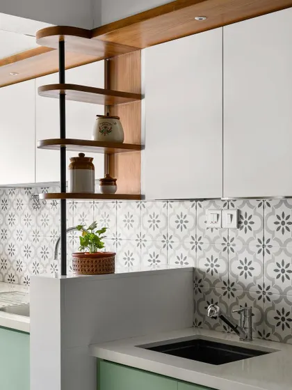 We call this the 'Garden of Eden' kitchen for its fresh green cabinetry and patterned floral tiles. The rotating corner shelf is a custom detail that adds both charm and utility.