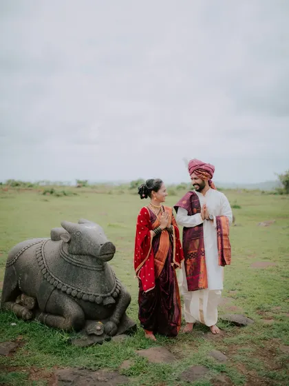 A candid moment between a couple standing next to a Nandi statue at a temple.