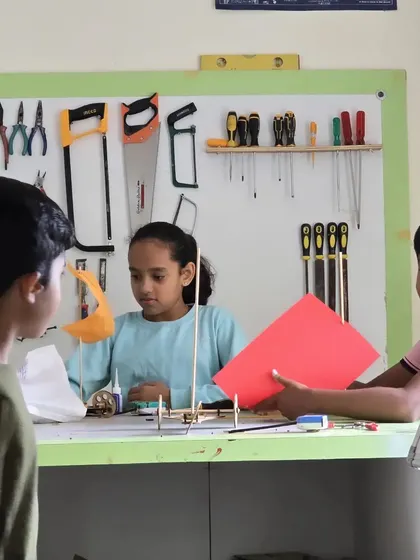 Students collaborate on a building project, using craft materials to understand engineering principles in a creative way.