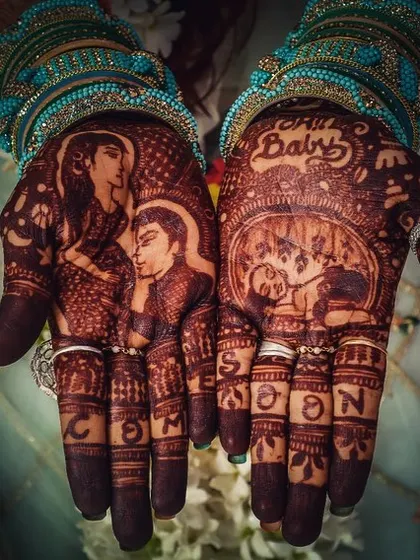 A stunning photo of a completed baby shower henna stain. The design features portraits of the parents to be, with the words 'Coming Soon' spelled out on the fingers, building excitement for the new arrival.