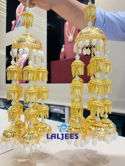 A beautiful pair of multi-tiered golden kaleeras with delicate white shell details, perfect for a grand bridal entry.