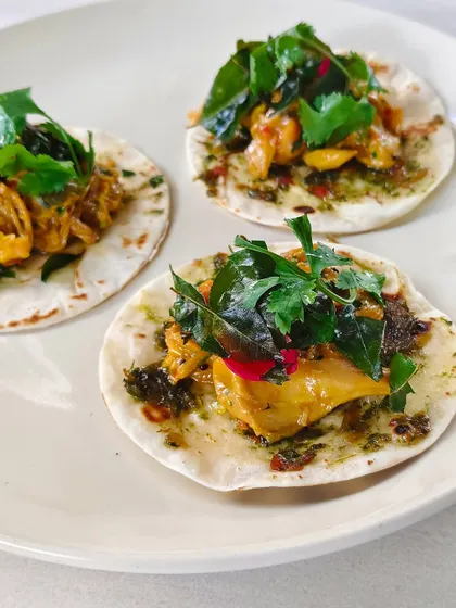 Mini chicken tacos on soft tortillas, topped with fresh cilantro. Mischief, mayhem, and mouthfuls.