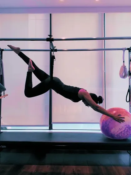 A variation of the previous pose, adding a leg bend to deepen the stretch and challenge stability further. The Cadillac allows for creative and beautiful movements.