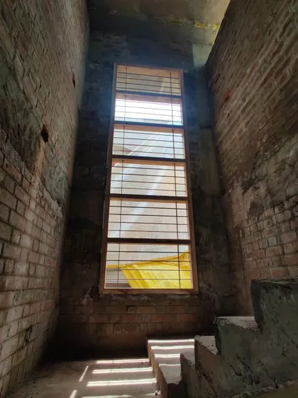 A tall, narrow window installed in a raw brick stairwell, designed to bring light deep into the core of the house.