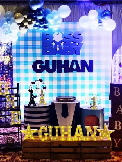 A stylish Boss Baby theme for Guhan's birthday. The setup includes a blue plaid backdrop, a shimmer wall, and lots of fun props like baby bottle silhouettes and money bags.