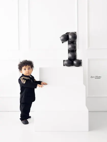 Standing tall for his first birthday portrait. This minimalist setup with clean white lines and a modern balloon number puts all the focus on the birthday boy.