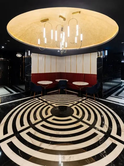 A striking feature in the INOX Jalosa lobby is this circular seating area, defined by a dramatic labyrinth-style floor inlay. The design creates a natural gathering point and a strong visual anchor in the space, complemented by a modern chandelier that casts a warm glow.