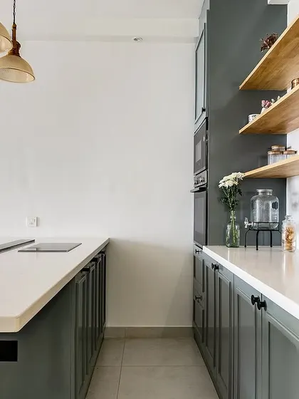 The dry kitchen features open wooden shelves and sleek grey cabinets, providing a mix of display and concealed storage.