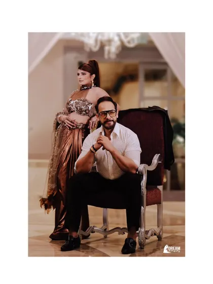 A regal portrait of Ajay and Kirti, with him seated and her standing, exuding power and style.