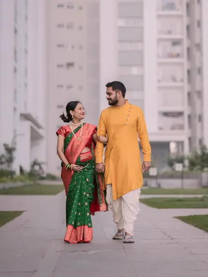 A full-length shot of an expecting couple walking hand-in-hand outdoors. Dressed in traditional Indian clothing, this photo captures a candid moment from their maternity photoshoot in Bangalore.