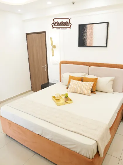 A cozy bedroom with a warm burnt orange bed frame. The design is simple and clean, with a focus on comfort. The bedside wall lamp adds a touch of modern style.