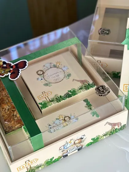 A beautifully packaged jungle themed hamper, perfect as a return gift for a "Wild One" birthday party. It includes a tea cake, burfi, and chocolate truffle pops.