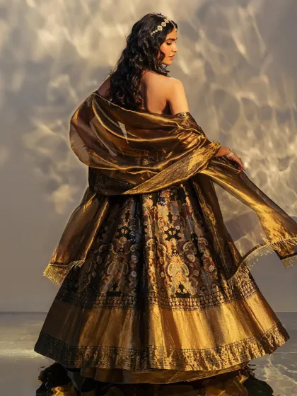 The back of a magnificent black and gold Benarasi lehenga. The sheer drama and beauty of the fabric make it a showstopper from every angle.