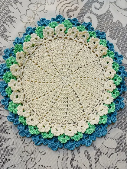 This placemat features cool tones of blue, green, and cream in its layered floral design. It’s perfect for creating a calm and serene table setting.