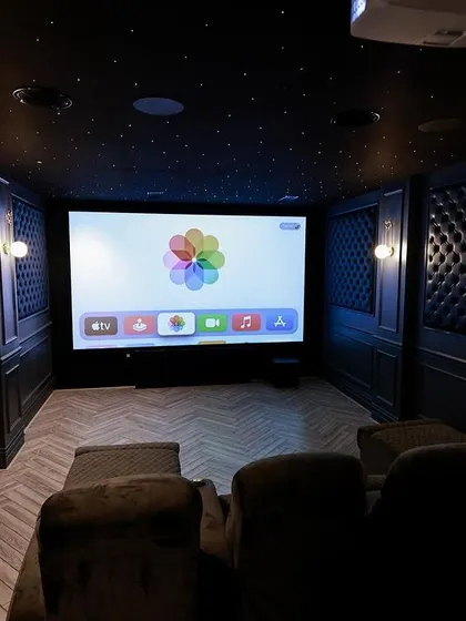 The view from the recliners in this European-style theater in Thoothukudi. The room features a starlit ceiling, wall sconces, and a large screen for a complete cinematic feel.