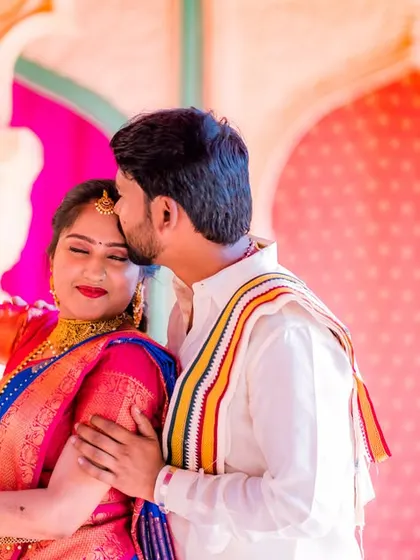 A sweet forehead kiss on a decorated swing. This candid moment captures the love and affection between the couple in a beautiful, traditional setting.