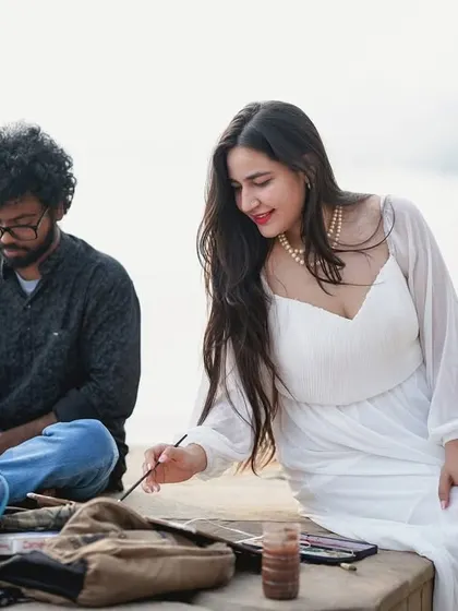 We can incorporate creative concepts into your pre-wedding shoot. Here, the bride-to-be tries her hand at painting by the ghats, adding a personal and artistic touch to their story.
