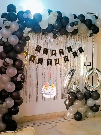 A stylish black, white, and silver balloon arch with a shimmer curtain for a 40th birthday.