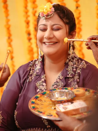 A close-up of the bride smiling as the haldi paste is applied. This shot is full of warmth and happiness.