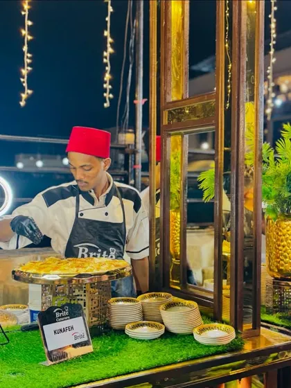 A chef preparing fresh Kunafeh, a traditional Middle Eastern cheese pastry, at a live station.