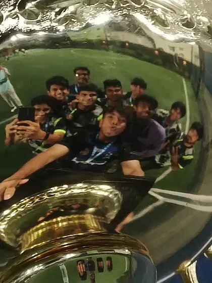 A creative shot of the team's reflection in the trophy. This represents our collective focus on the prize and our shared journey.