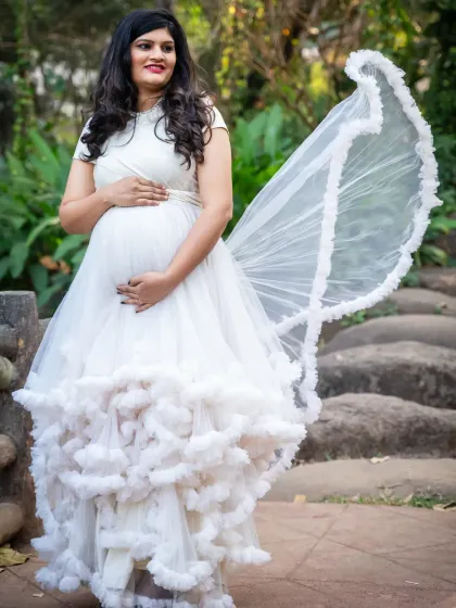 A solo portrait of the mom-to-be in a stunning white ruffled gown. The way the fabric flows creates a beautiful, angelic look.
