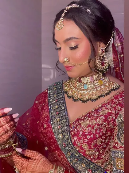 The bride adjusting her jewelry, a candid moment that shows off her intricate henna and beautiful makeup.