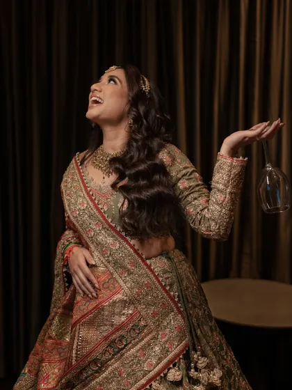 A bride laughing with a wine glass in hand, full of joy and ready to celebrate her Mehendi.