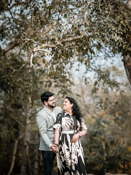 A lovely portrait of the couple looking at each other amidst the trees. The soft, natural light and green surroundings create a peaceful and romantic atmosphere.