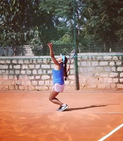 A female player demonstrates excellent serving form during the Tennis360 Open Tournament.
