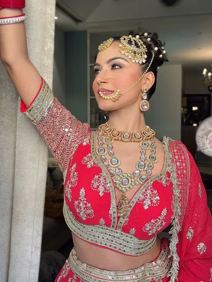 A close-up of the intricate silver embroidery on a red bridal blouse, paired with a layered kundan necklace, showcasing our attention to detail.