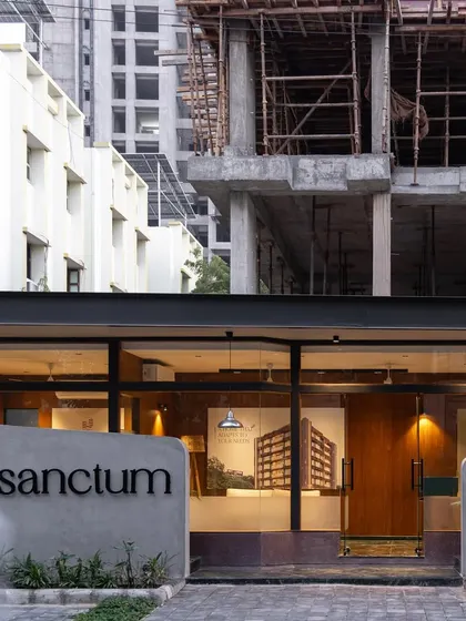 **Sanctum Site Office, Ahmedabad:** This view shows the site office in its context, with the larger residential structure under construction behind it. The office acts as a tangible preview of the material quality and design sensibility that clients can expect.