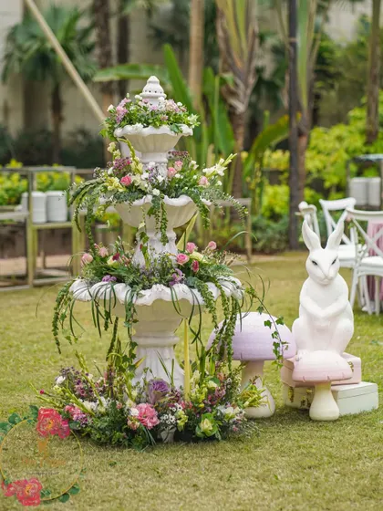 A beautiful white fountain overflowing with flowers and greenery, serving as a stunning centerpiece for the garden party.
