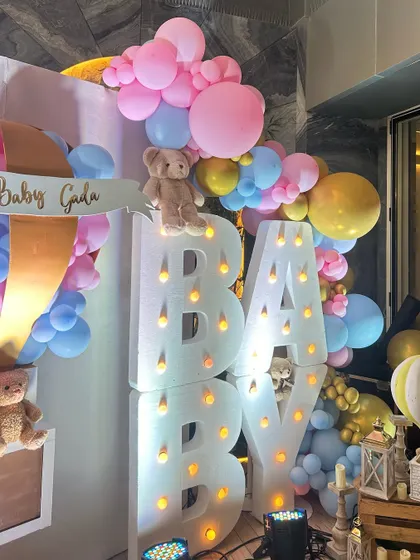 This whimsical baby shower featured large marquee letters, teddy bears nestled in pastel balloon clouds, and a custom hot air balloon prop, creating a dreamy and joyful atmosphere.