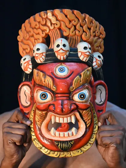 This Nepalese mask, with its third eye and crown of skulls, is a powerful mythical being believed to ward off malicious forces. The intricate carving and painting make it a striking piece of cultural art.