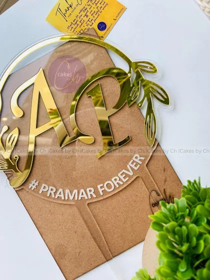 A premium glass-like acrylic topper with initials "A" and "P" and the phrase "#PRAMAR FOREVER," perfect for modern weddings.