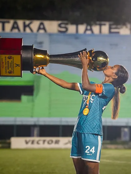 The sweet taste of victory. A player kisses the championship trophy, a powerful and iconic image that captures the personal connection and passion involved in winning.