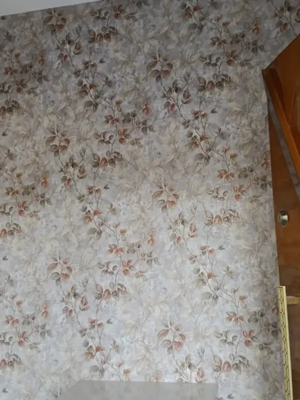This wallpaper features a dense pattern of small leaves and branches in muted, earthy tones. It provides a rich texture and a subtle natural element to the room.