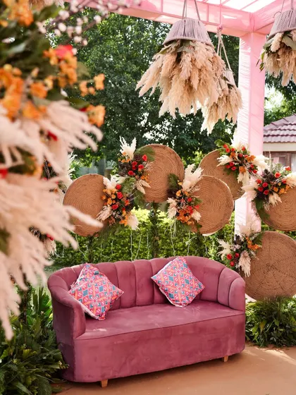 A detailed shot of the Mehendi seating, highlighting the blend of textures from the plush sofa, woven backdrops, and fluffy pampas grass.