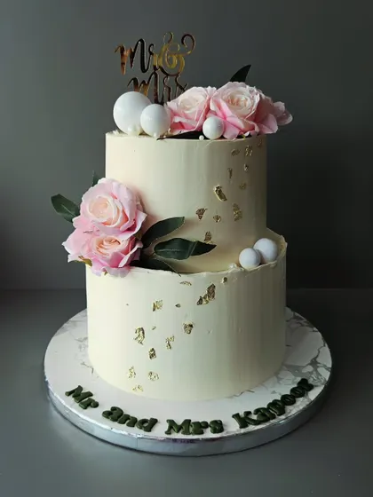 Together forever. A simple and elegant two-tier pineapple cake for Mr. and Mrs. Kapoor, decorated with fresh pink roses and gold leaf.