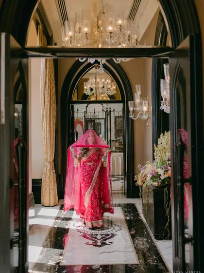 A grand entrance. The bride, veiled and framed by the magnificent arches of the Taj Mahal Palace, creates a dramatic and unforgettable image.