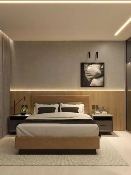 A full view of a master bedroom with a smoked glass sliding wardrobe. The linear LED lighting on the ceiling and along the headboard adds a sleek, modern touch.