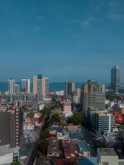 A panoramic view of the Colombo cityscape against a clear blue sky, with the sea in the distance. This shot showcases the sprawling nature of the city.