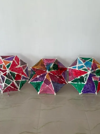 The finished masterpieces. A lineup of the vibrant, colourful umbrellas painted by the children, each one a unique work of art.