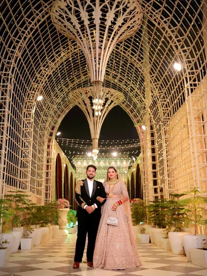 A classic reception portrait of Tanu and Kunal under a beautifully lit arched walkway.